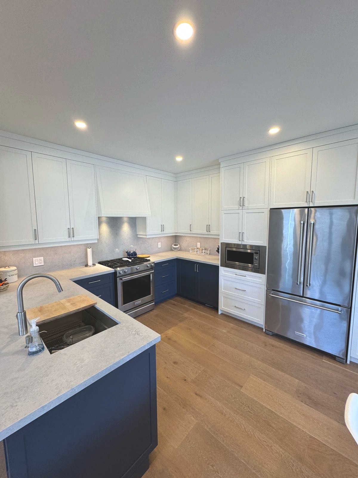 Open-concept kitchen, dining and living with navy island and shiplap walls
