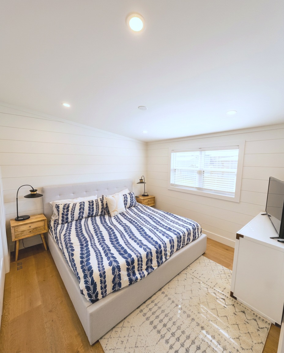 Primary bedroom with shiplap walls and wide plank hardwood floors
